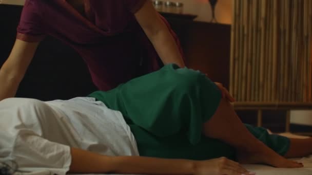 Tajski Masażysta robi masaż kobiecie w salonie spa. Azjatka piękna kobieta coraz tajski masaż ziołowy kompres masaż w spa.She jest bardzo zrelaksowany. Piękno tajski masaż koncepcja — Wideo stockowe