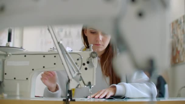 Vooraanzicht van vrouwelijke mode-ontwerper werken met naaimachine in workshop — Stockvideo