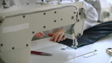 Kadın terzi dükkânda dikiş makinesi üzerinde çalışıyor. Elbise dikmek için. Birlikte dikiş atölyesinde çalışıyoruz..
