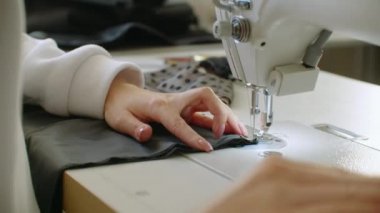 Dikiş Makinesi İğnesi Harekete Geçiyor. Dikiş makinesinin iğnesinin yakın çekimi hızla yukarı ve aşağı hareket eder. Terzi dikiş atölyesine siyah kumaş dikiyor. Kumaş dikme süreci