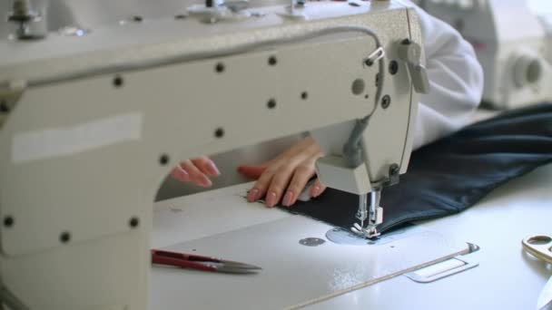 Vrouwelijke naaister werkt aan een naaimachine in de winkel voor het naaien van kleding. Samenwerken in een naaiatelier. — Stockvideo