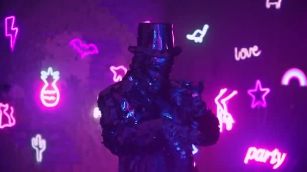 Un uomo balla nella luce del neon in una tuta di vetro. Brillante abito argento scintillante e luce blu viola al neon. Festa di Capodanno . — Video Stock