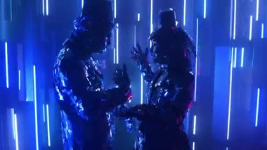 Neon ışıklı çift metalik parlak çift birlikte dans ediyor. Modern cam insanlar, gösteriler neon mavisi pembe ışıkla gösteriliyor. Komik bir dans. Kulüp için müzik ekran koruyucusu.
