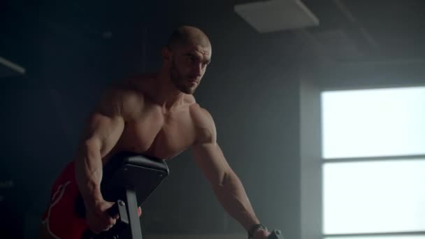 A man in a fitness club pulls a barbell in a tilt performing exercises for the muscles of the spine — Stock Video