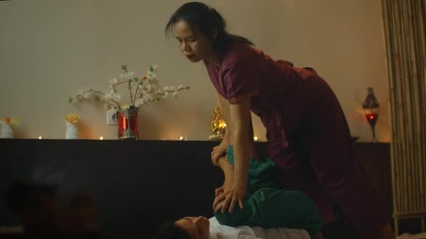 Young woman lying down while enjoying the acupressure techniques of traditional Thai massage at luxury spa and wellness center. — Stock Video