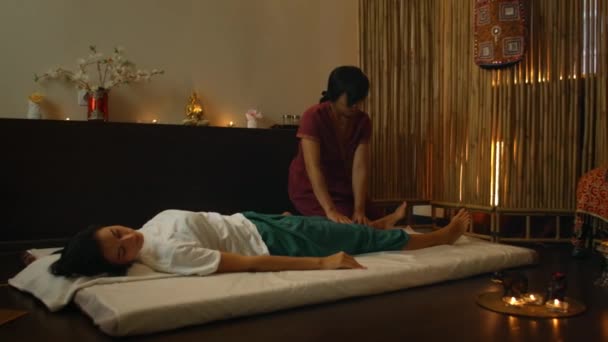 Une femme caucasienne se détend avec un massage thaï au spa. Femme asiatique dans la mort traditionnelle effectue un massage sur le dos — Video