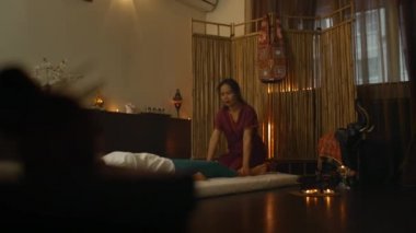 Asyalı bir kadın, yalancı, güzel bir Avrupalı kızın sırtına geleneksel Tayland masajı yapıyor. Kayropraktör alternatif yöntemlerle tedavi üretir