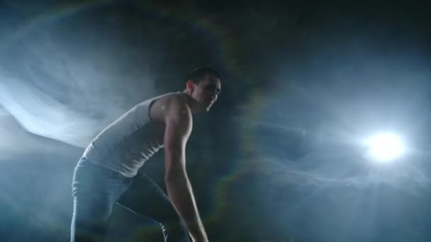 现代芭蕾，一个男人从舞台上坐着的姿势跳着翻跟斗，在黑暗的舞台上，在聚光灯下的烟雾中旋转着对着摄像机。 剧场舞台上的现代编舞. — 图库视频影像