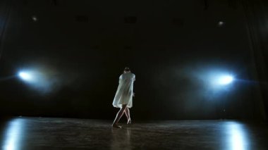Modern bir balerinin müzikal solo performansından dinamik sahneler. Sahne ışıkları altında yavaş çekimde dans etmek. Dans müzikali. Ay ışığında dramatik bir sahne