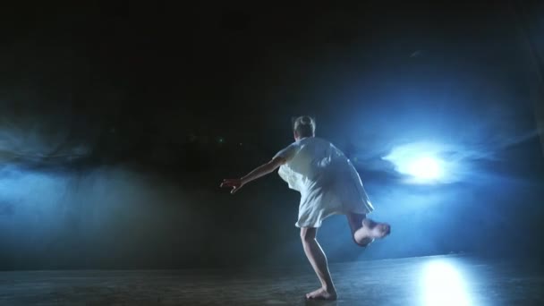 Eine dramatische Szene des modernen Balletts, eine einsame Ballerina im weißen Kleid führt Tanzschritte mit moderner Choreographie aus — Stockvideo