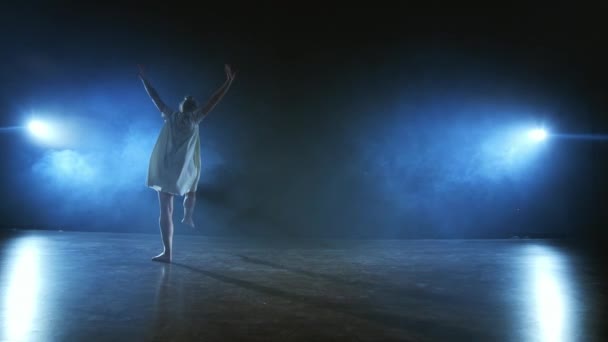 Giros dramáticos y volteretas de un bailarín de ballet moderno de un musical. Una mujer soltera baila emocionalmente en el escenario sobre un fondo oscuro con humo en el centro de atención en cámara lenta — Vídeos de Stock
