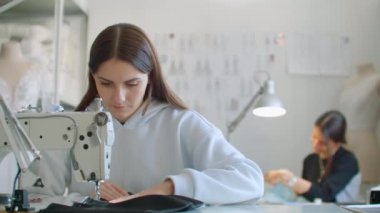 Kıyafetlerin terziliği. Dikiş makinesinde elbise dikme atölyesinde iş yerinde terziler. Terziler atölyede elbise dikerler. İki kadın terzi. Dikiş işinde dressmaking