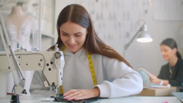 Adaptación de la ropa. Las costureras en el trabajo en el taller de costura de ropa en la máquina de coser. Los modistos cosen la ropa en el taller. Dos costureras. La confección en el negocio de costura — Vídeos de Stock