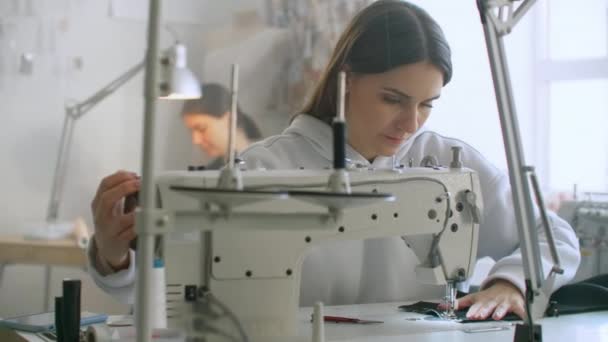 Schneiderei von Kleidung. Näherinnen bei der Arbeit in der Näherei nähten Kleidung an der Nähmaschine. Schneiderin näht Kleidung im Atelier. zwei Schneiderinnen. Schneiderei im Nähgeschäft — Stockvideo