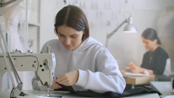 Schneiderei von Kleidung. Näherinnen bei der Arbeit in der Näherei nähten Kleidung an der Nähmaschine. Schneiderin näht Kleidung im Atelier. zwei Schneiderinnen. Schneiderei im Nähgeschäft — Stockvideo