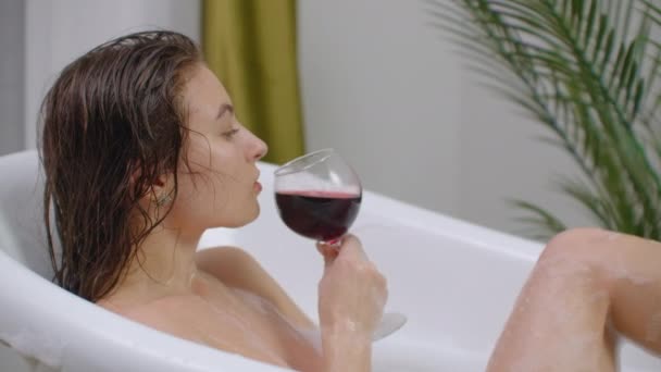 Beba vinho deitado no banho, deite-se em um banho quente com vinho tinto e não pense nos problemas. Gestão do stress — Vídeo de Stock