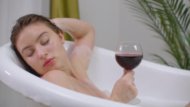 Beautiful woman relaxing in bubble bath lying in bathtub. Beauty care, leisure activity and healthcare concept — Stock Video