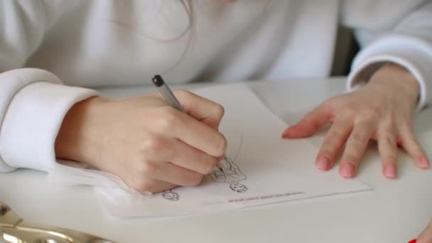 Σχεδιαστής ρούχων κάνει ένα περίγραμμα των ρούχων με ένα στυλό τσόχινη άκρη. γυναικεία χέρια κοντά. — Αρχείο Βίντεο