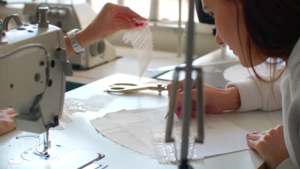 Primer plano de dos mujeres jóvenes que trabajan como diseñadores de moda y bocetos de dibujo para la ropa en el taller . — Vídeo de stock