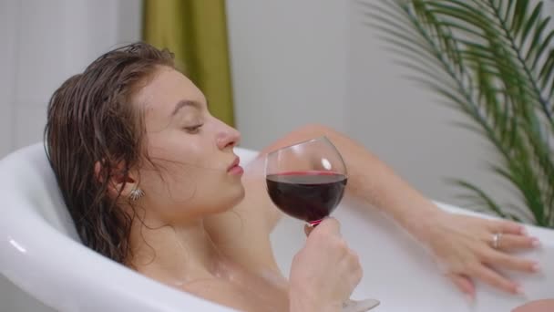 Lucha contra el estrés para la liberación del trabajo diario de las preocupaciones por acostarse en el baño y disfrutar del vino y el agua caliente con espuma . — Vídeo de stock