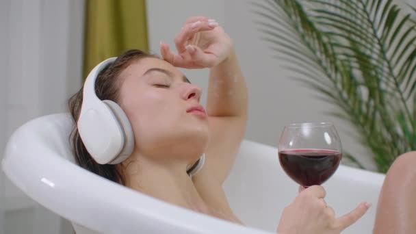 Bara koppla av. Innehåll vacker ung kvinna lyssnar på musik och stänga ögonen medan du tar ett bad — Stockvideo