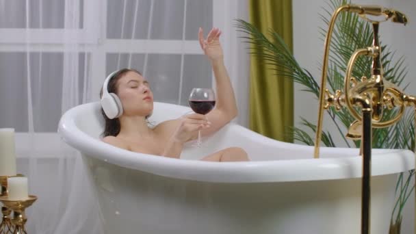 Po prostu zrelaksuj się. Treść piękna młoda kobieta słuchając muzyki i zamykając oczy podczas kąpieli — Wideo stockowe