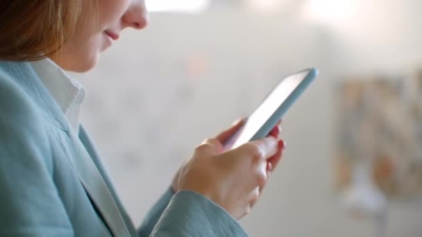 Gros plan : une jeune femme designer femme d'affaires dans un studio de couture avec un téléphone portable dans un atelier de couture écrire des messages aux clients .