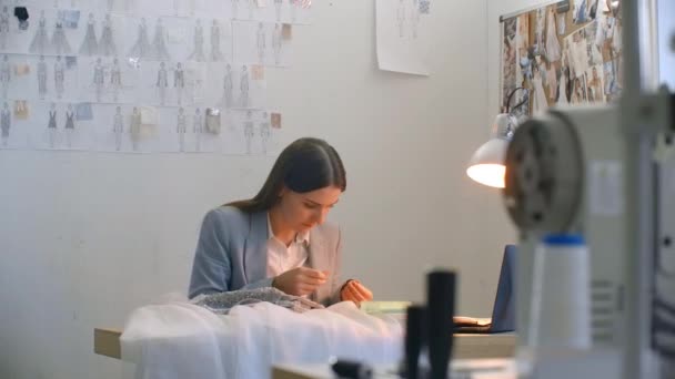 Uma jovem designer fazendo um vestido no vestido Studio. Costurar contas de costura Estúdio e jóias. Seamstress decora um vestido no Estúdio — Vídeo de Stock