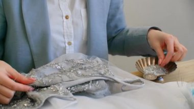 Kadın tasarımcı elbisesi elbiseyi kristallerle süslüyor. Terzi atölyesinde özel bir elbise yapıyor. Küçük bir iş. Moda tasarımcısı