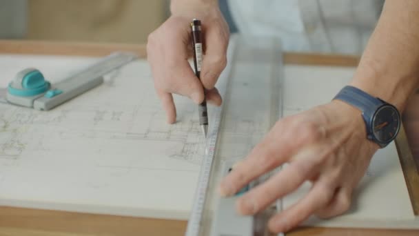 El ingeniero dibuja edificios sobre la mesa usando un lápiz y una regla. Un arquitecto crea un diseño de edificio sobre papel usando un marcador y una regla — Vídeos de Stock