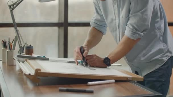 Um arquiteto masculino cria um desenho de um edifício sobre papel. Estudar o design das instalações, criar móveis e casas. Grande escritório moderno desenhar no quadro negro — Vídeo de Stock