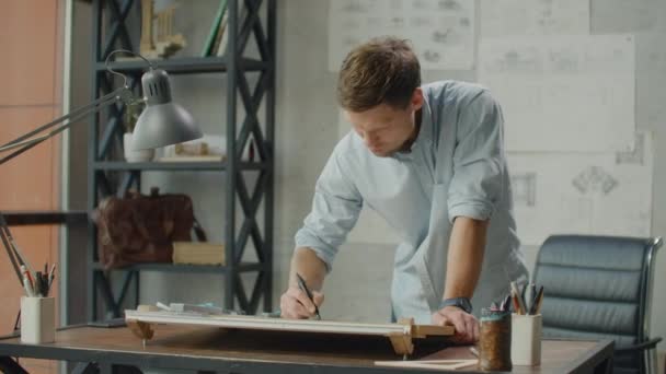 Architect man sits at drafting table in modern industrial office during the day — 비디오