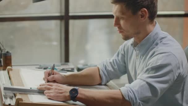 Arquiteto homem de pé trabalhando com plantas esboçando um projeto de construção em madeira mesa em casa office.Construction design concept.vintage tom de cor . — Vídeo de Stock