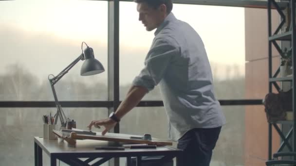 Architect man sits at drafting table in modern industrial office during the day — 图库视频影像