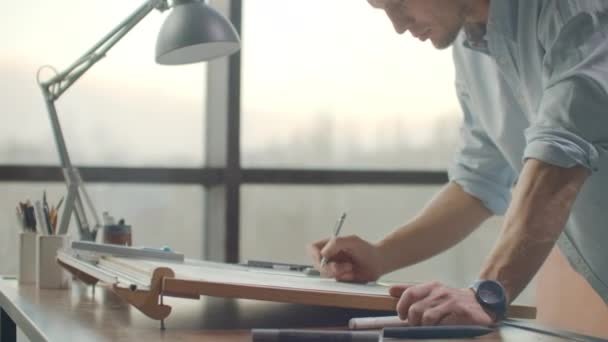 Инженер рисует здания на столе карандашом и линейкой. Архитектор создает дизайн здания на бумаге с помощью маркера и линейки — стоковое видео