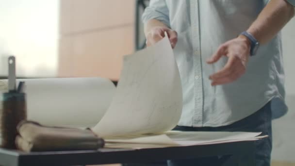 Hipster ingenieur werkt met blauwdruk. Schiet van bovenaf. Jonge bouwkundig ingenieur aan het werk. Een man met baard maakt schetsen. Loft stijl, minimalistisch interieur, tekeningen op tafel. — Stockvideo