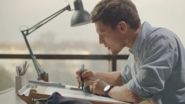 Ingenieur tekent gebouwen op tafel met potlood en liniaal. Een architect maakt een gebouw ontwerp op papier met behulp van een marker en liniaal — Stockvideo