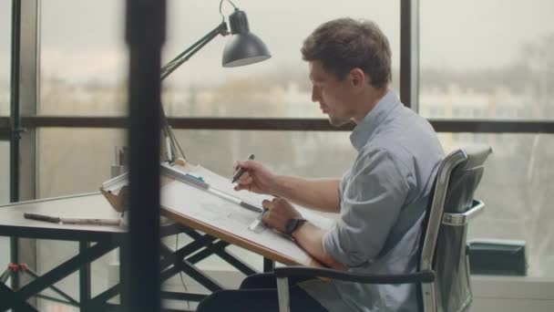 Architect man Standing working with blueprints sketching a construction project on wood desk at home office.Construction design concept.vintage color tone. — Stockvideo