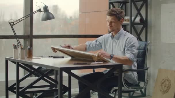 Architetto uomo In piedi a lavorare con cianografie schizzo di un progetto di costruzione su scrivania in legno a casa office. . — Video Stock
