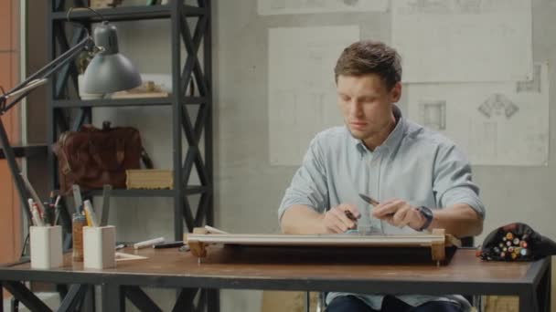 Arquiteto homem senta-se à mesa de esboço no escritório industrial moderno durante o dia — Vídeo de Stock