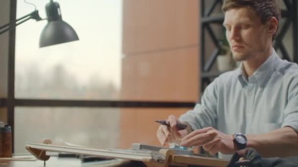 Architect man sits at drafting table in modern industrial office during the day — Wideo stockowe