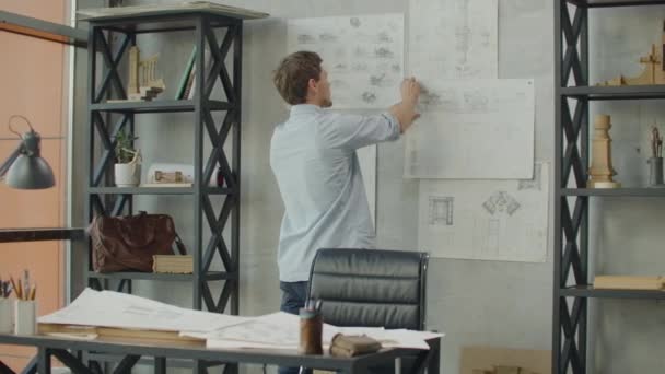Stylowe biuro w stylu strychu. Biznesmen robi notatki na ścianie. Pomysł na biznes, projekt, mapa umysłu. Projektant pracuje w biurze strychu i robi notatki na rysunkach na ścianie — Wideo stockowe