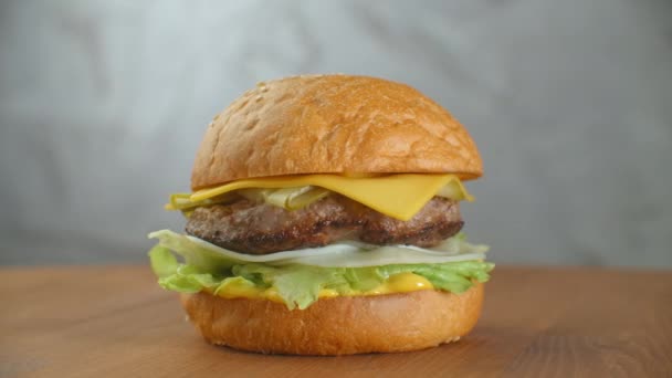 쇠고기 돈 까 스, 토마토, 버섯, 녹 인된 치즈와 오이 훌륭한 햄버거 밝은 배경에 나무 보드 회전 — 비디오