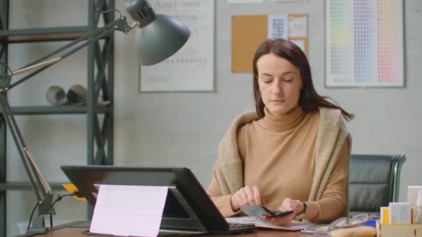 A young designer girl draws on a modern graphic screen using a workstation in an office with large Windows. Create logo design and graphics. — ストック動画