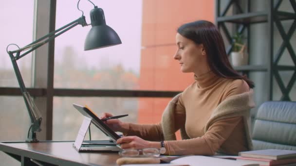Bir kadın grafik tasarımcı, geniş pencereli ve boyalı bir ofiste bir stil ve bilgisayar ekranı kullanarak çalışır. Tasarımcılar için dokunmatik ekranlı çalışma istasyonu. — Stok video