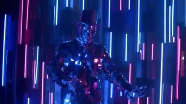 Işığı yansıtan cam bir adam mor ve mavi renkli neon bir duvara karşı dans eder.