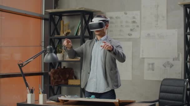 Ingeniero masculino en la oficina en un casco de realidad virtual utiliza gestos para gestionar el proyecto sin salir de la oficina. Control de construcción. Proyecto de diseño del edificio y del interior . — Vídeo de stock