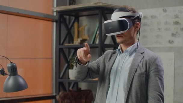 Joven ingeniero masculino en oficina en casco de realidad virtual con manos realiza movimientos imitando el trabajo de interfaz gráfica — Vídeos de Stock