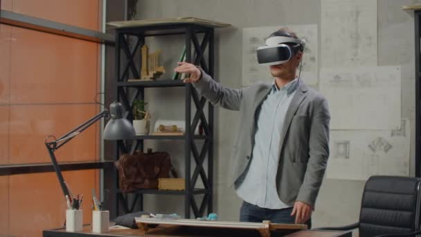 Männliche Architekt im Büro in Virtual-Reality-Helm verwendet Gesten, um ein Projekt zu verwalten, ohne das Büro zu verlassen. Baukontrolle. Entwurfsprojekt des Gebäudes und des Innenraums. — Stockvideo