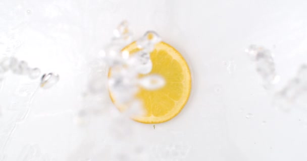 Fresh lemon on the top view the water is pouring on a white background — Stock Video